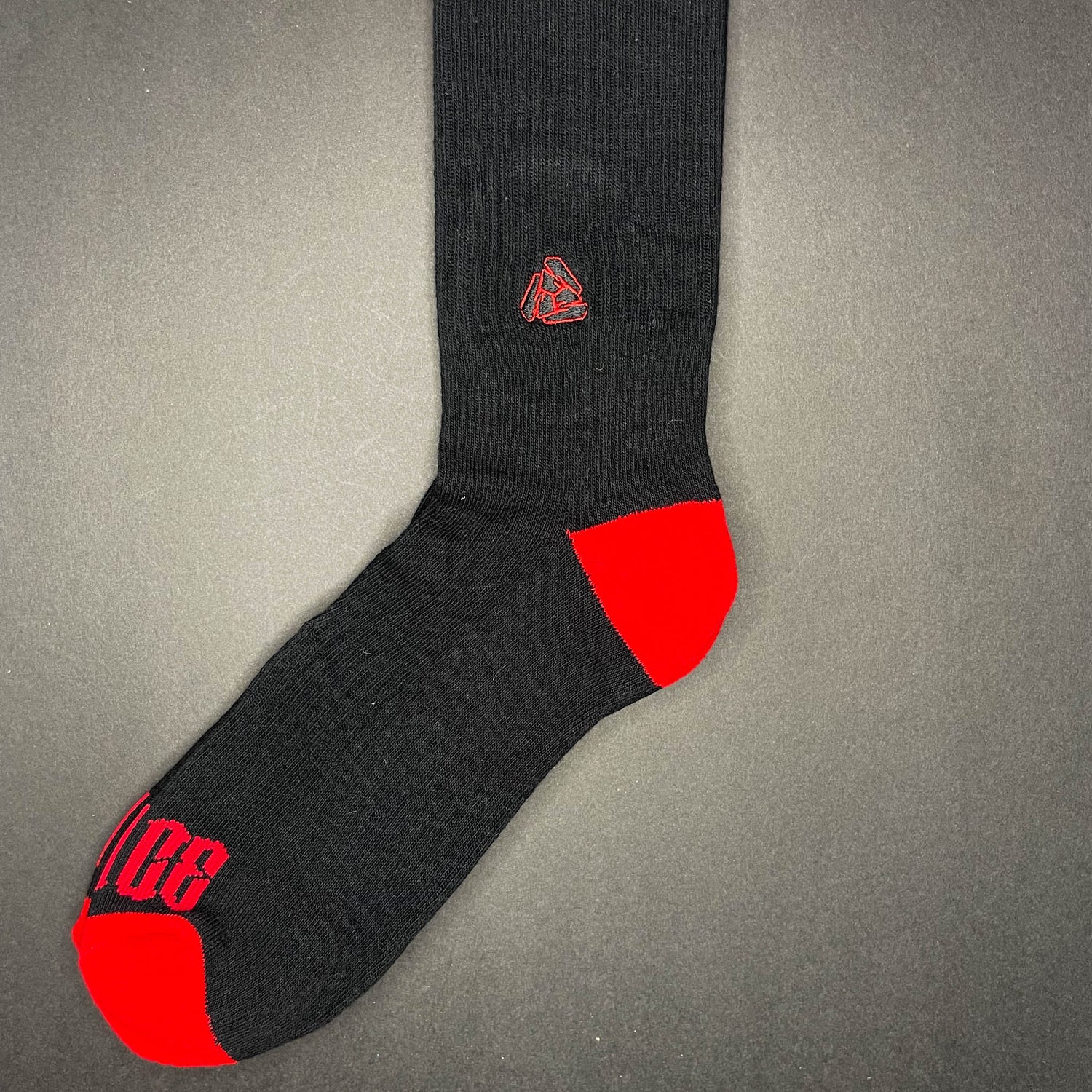 Side view of Menace Clothing Hood Rat red and black knee high socks with Menace on toes and Tri M logo on side.